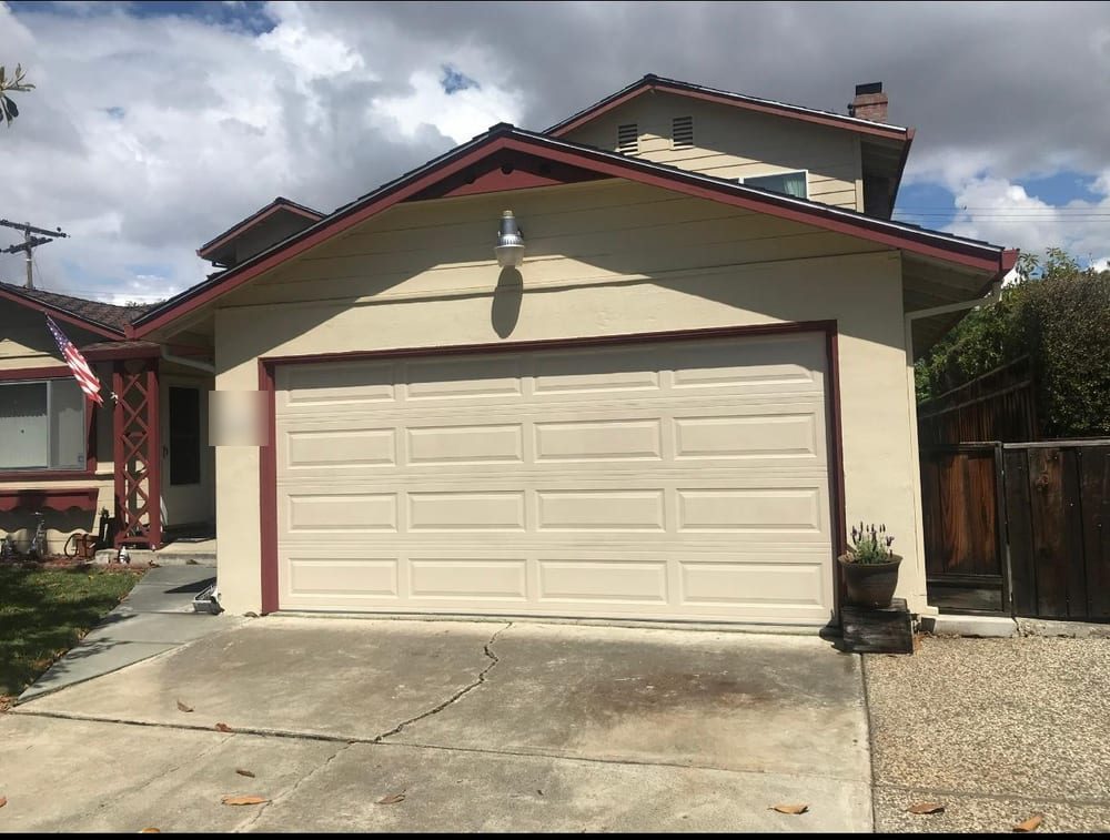 Cream sectional garage door on a two-storey Fremont-area house with a sloped driveway