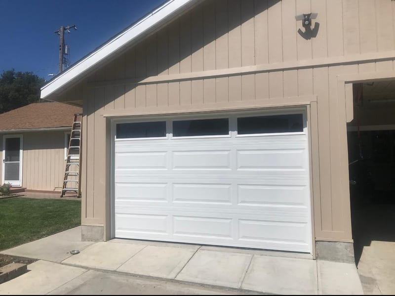 New white sectional garage door on a beige house